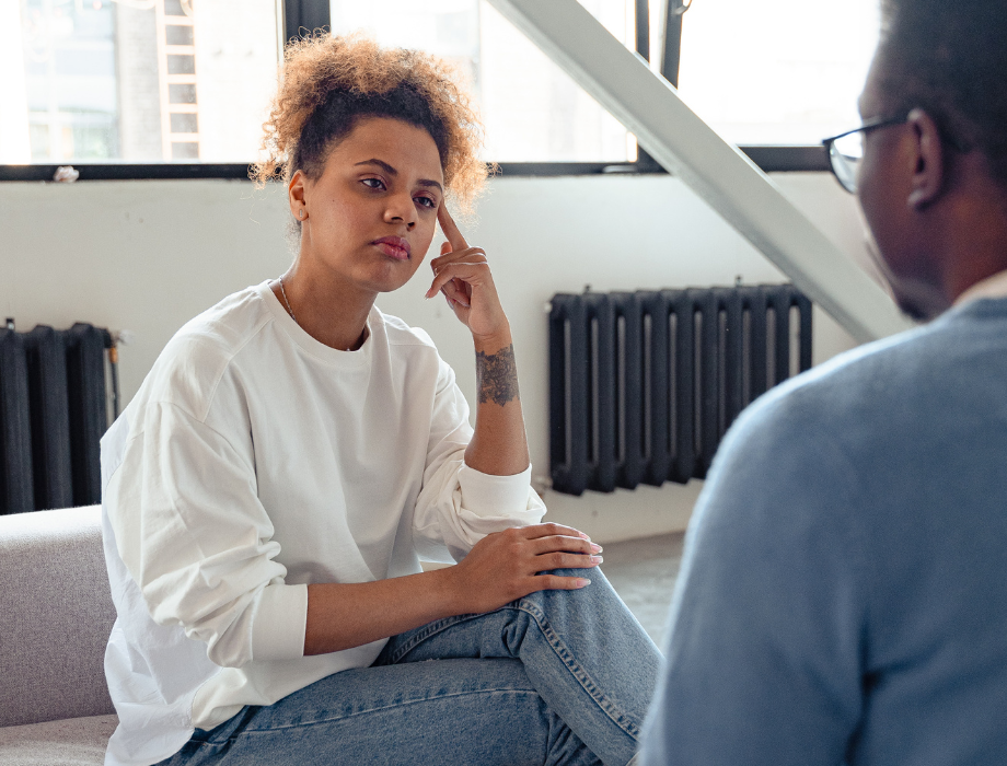 Woman sitting on couch listening to therapist offer advice on what she can do for a friend or personally after an abusive partner apologizes.